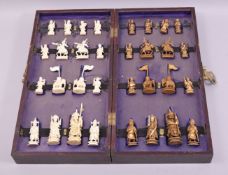 A CHINESE CARVED AND STAINED IVORY FIGURAL CHESS SET, housed in a folding chess board.