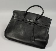 A LARGE BLACK LEATHER BAG with chrome lock and dust cover. 17ins long.