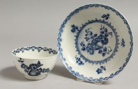 AN 18TH CENTURY WORCESTER TEABOWL AND SAUCER painted in blue with fruit and wreath pattern, crescent