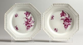 A PAIR OF 19TH CENTURY BERLIN PLATES painted with flowers, in pink with pierced octagonal borders.