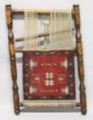 A PERSIAN CARPET, PART WEAVED CARPET on a turned wood frame. 3ft 4ins x 2ft 2ins.