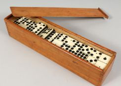 A SET OF EBONY AND BONE DOMINOES in a box, 2ins long