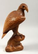 A GOOD CARVED WOOD EAGLE standing on a rock, 14ins high.