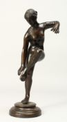THE ANTIQUE A BRONZE FIGURE OF A STANDING NUDE on one leg, on a circular base. 10ins high.