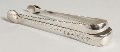 TWO GEORGE III BRIGHT CUT SUGAR TONGS, London circa.1800, maker R C & London 1792, maker T S.
