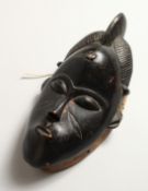 A CARVED WOOD TRIBAL MASK. 12ins long.