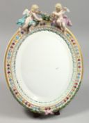 A GOOD MEISSEN OVAL MIRROR with two cupids. Cross swords mark in blue.