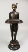A CAST BRONZE FIGURE OF A STANDING MALE, his arms outstretched, holding a tray, on a circular