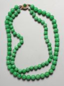 A GOOD TWO ROW JADE NECKLACE with gold clasp.