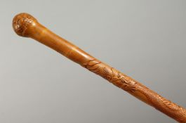 A JAPANESE ENGRAVED AND CARVED BAMBOO WALKING CANE, carved with an entwined dragon. 35ins long.