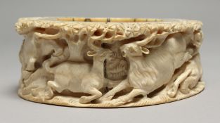 A MANMOUTH CARVED BONE OVAL DISC carved with deer and tiger. 5.25ins x 4.25ins x1.75ins