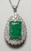 A SUPERB 18CT WHITE GOLD PENDANT set with a large emerald surrounded by a diamond.