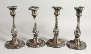 A SET OF FOUR ROCCOCO STYLE PLATED CANDLESTICKS. 10ins high.