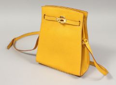 A YELLOW LEATHER BAG with gilt lock and long strap. 7ins x9.5ins.