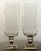 A GOOD PAIR OF GLASS STORM LAMPS on square stepped bases, 16ins high.