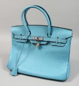 A LIGHT BLUE LEATHER BAG with chrome lock. 13ins x11.5ins. with dust cover.