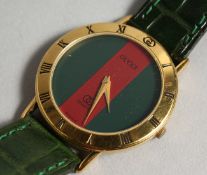 A GUCCI RED FACE WRIST WATCH with leather strap.
