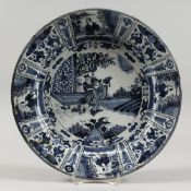 AN 18TH CENTURY DUTCH DELFT TIN GLAZED CIRCULAR DISH, painted with figures in a landscape in the