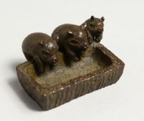 THREE JAPANESE BRONZE PIGS IN A TROUGH.