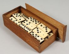A SET OF EBONY AND BONE DOMINOES and a case. 1.25ins long.