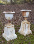 A GOOD PAIR OF VICTORIAN WHITE PAINTED CAST IRON GARDEN URNS ON STANDS 3ft 2ins high.
