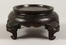 A CHINESE BRONZE CIRCULAR VASE STAND supported on four grotesque legs. 5ins diameter.