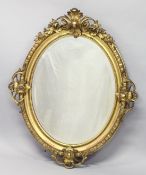 A GOOD 19TH CENTURY GILT FRAMED OVAL MIRROR, the heavy moulded frame applied with four pierced,