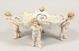 A SITZENDORF PEDESTAL PIERCED COMPORT with four winged cupid supports. 8ins diameter.