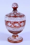 A BOHEMIAN RUBY CUT GLASS BOWL AND COVER etched with fruiting vines. 7ins diameter.