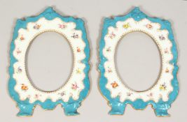 A PAIR OF DRESDEN PORCELAIN OVAL PHOTOGRAPH FRAMES, blue border painted with flowers. 9ins x 6ins