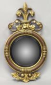 A REGENCY CONVEX GILTWOOD MIRROR, with Fleur de Lys cresting, a moulded frame with carved decoration
