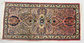 A SMALL PERSIAN DESIGN RUG, pink ground with a design of stylised palmettes. 4ft 6ins x 2ft 3ins.