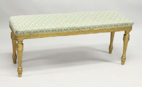 A LONG 19TH CENTURY GILTWOOD FRENCH STOOL with padded top on fluted legs. 3ft 10ins long, 1ft 3ins