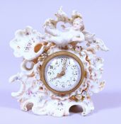 A SMALL CONTINENTAL PORCELAIN CLOCK with cupids, flowers and scrolls. 5.5ins high.