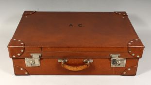 A GENTLEMAN'S LEATHER TRAVELLING SUITCASE by FINNIGENS, LONDON, with silver top bottles and brushes.