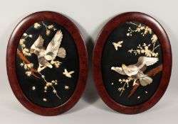 A GOOD PAIR OF JAPANESE OVAL LACQUER PANELS inset with birds and foliage in ivory and mother of