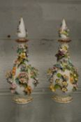 A pair of floral encrusted bottles with stoppers.
