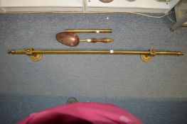 A brass pole with brackets, a brass and copper scoop and a cylindrical container.
