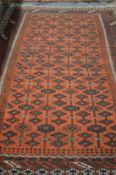 A long Persian carpet, rust ground with stylized decoration.