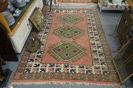 A Turkish carpet, pink ground with three central large lozenge shaped motifs.