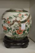 A Chinese Famille Jaune jar on a hardwood stand.