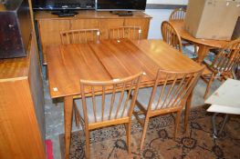 A mid century walnut extending dining table with one leaf together with four matching stick back