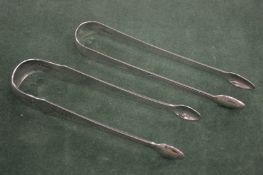 TWO GEORGE III BRIGHT CUT SUGAR TONGS. London 1792, maker A D & 1790 , maker W S.