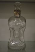 An hourglass decanter with silver collar.