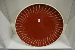A large Susie Cooper charger, red glaze with feather decorated border.