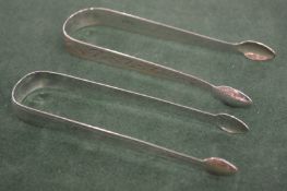 TWO GEORGE III BRIGHT CUT SUGAR TONGS. Maker N S & CO. and London 1805, maker A B +.