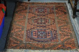 A small Persian rug, rust ground with three central large motifs.