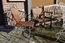 A pair of wrought iron and rattan garden armchairs.