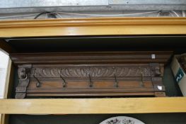 A carved oak cornice with brass hat and coat hooks together with a hunting tapestry.