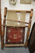 A wooden loom mounted with a part made Persian rug.